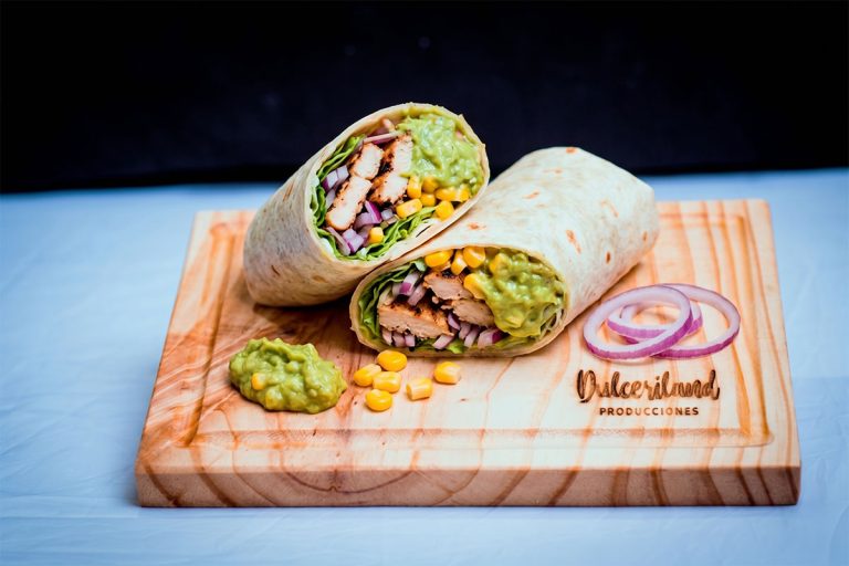 Fajita rellena con pollo, cebolla morada, lechuga, choclo y guacamole sobre tortilla doblada